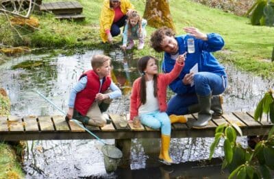 Adults With Children On Bridge At Outdoor Activity Centre